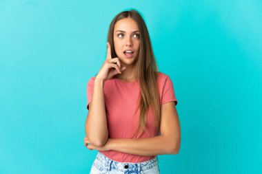 Soyutlanmış mavi arka planda genç bir kadın bir fikir düşünüyor.