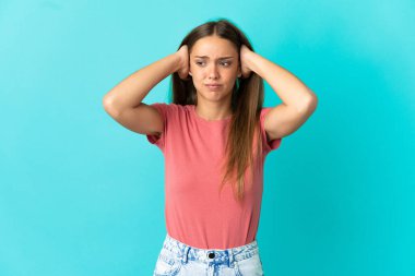 İzole edilmiş mavi arka planı olan genç bir kadın hayal kırıklığına uğramış ve kulaklarını kapatmış.