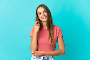 Genç bir kadın mavi arka planda gülüyor.