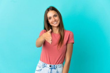 Soyutlanmış mavi arka planda genç bir kadın iyi bir anlaşma için el sıkışıyor.