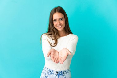 İzole edilmiş mavi arka plan üzerinde genç bir kadın bir ilan vermek için avucunun içinde hayali bir alan tutuyor.