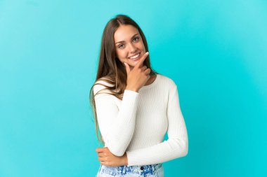 Soyutlanmış mavi arka plan mutlu ve gülümseyen genç bir kadın.