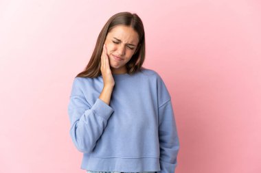 İzole edilmiş, pembe arka planda diş ağrısı olan genç bir kadın.