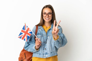 Birleşik Krallık bayrağını izole edilmiş beyaz arka planda tutan genç İspanyol kadın gülümsüyor ve zafer işareti gösteriyor.