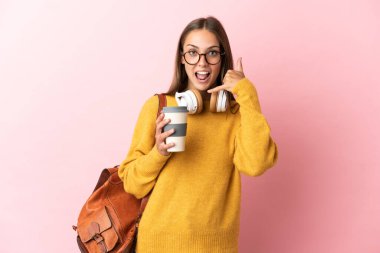 Soyutlanmış pembe arka planda genç bir bayan telefon jesti yapıyor. Bana geri dönüş işareti ver.