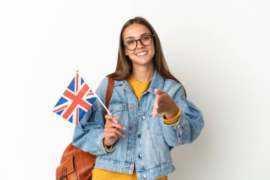 Birleşik Krallık bayrağını tutan genç İspanyol kadın izole edilmiş beyaz arka planda iyi bir anlaşma için el sıkışıyor.