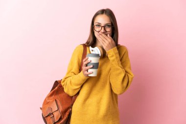 Soyutlanmış pembe arka planda genç bir bayan mutlu ve gülümsüyor, elleriyle ağzını kapatıyor.