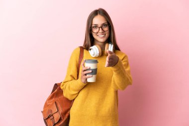 Tecrit edilmiş pembe arka planda genç bir bayan iyi bir anlaşma için el sıkışıyor.