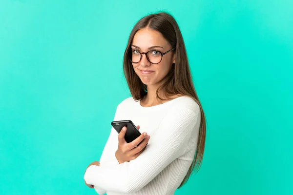 Young Woman Isolated Blue Background Holding Mobile Phone Arms Crossed — Φωτογραφία Αρχείου