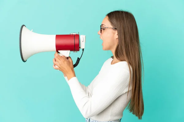 Jonge Vrouw Geïsoleerde Blauwe Achtergrond Schreeuwt Door Een Megafoon Iets — Stockfoto