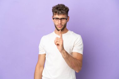 Mor arka planda izole edilmiş beyaz adam hayal kırıklığına uğramış ve ön tarafı işaret ediyor.