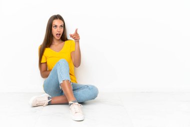 Genç kız yerde oturuyor ve işaret ediyor.