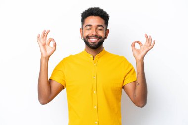Zen pozisyonunda beyaz arka planda izole edilmiş genç Brezilyalı adam.
