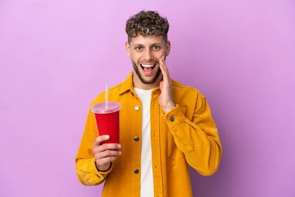Young Blonde Man Holding Soda Isolated Purple Background Surprise Shocked — 스톡 사진