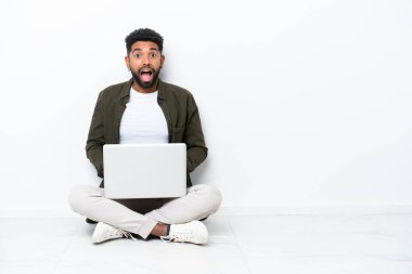 Yerde dizüstü bilgisayarı olan genç Brezilyalı bir adam. Yüzünde şaşkınlık ifadesi olan beyaz tenli bir adam.