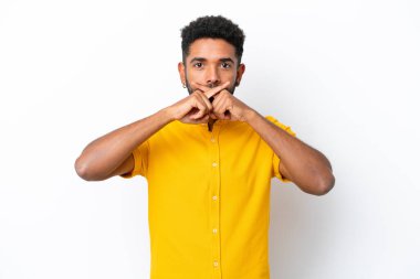 Beyaz arka planda izole edilmiş genç Brezilyalı bir adam sessizlik işareti gösteriyor.
