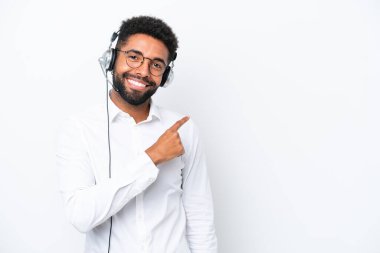Tele pazarlamacı Brezilyalı beyaz arka planda izole edilmiş bir kulaklıkla çalışan bir adam bir ürün sunmak için kenarı işaret ediyor
