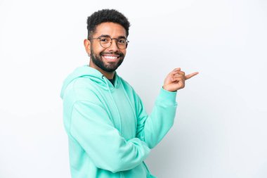 Beyaz arka planda izole edilmiş genç Brezilyalı adam parmağını yana doğru gösteriyor.