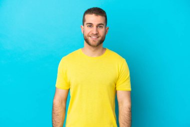 Mavi arka planda izole edilmiş yakışıklı beyaz adam gülüyor.