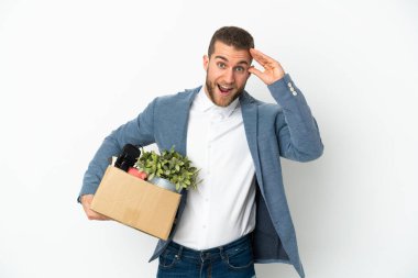 Beyaz arka planda izole edilmiş şeylerle dolu bir kutuyu alıp sürpriz bir ifadeyle hareket eden genç beyaz tenli.