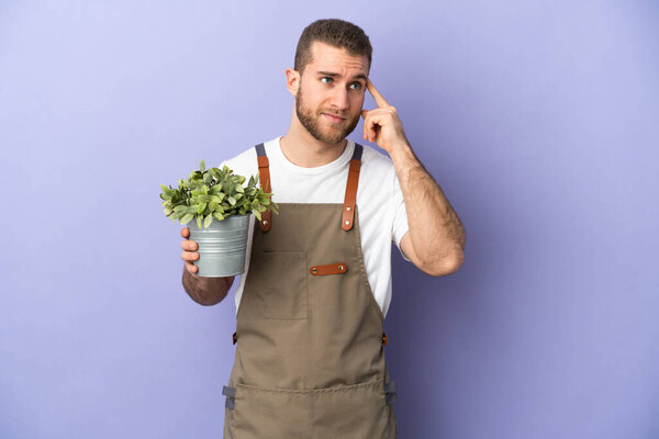 Gardener caucasian man holding a plant isolated on yellow background having doubts and thinking