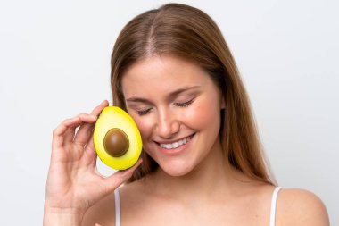 Beyaz arka planda izole edilmiş beyaz bir kadın elinde bir avokado tutarken gülümsüyor. Portreyi kapat