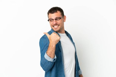 İzole edilmiş beyaz arka plan üzerinde Brezilyalı bir adam bir ürün sunmak için kenarı işaret ediyor