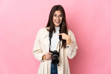 Genç fotoğrafçı Brezilyalı kız pembe arka planda izole edilmiş ve yüzünde sürpriz bir ifade var.