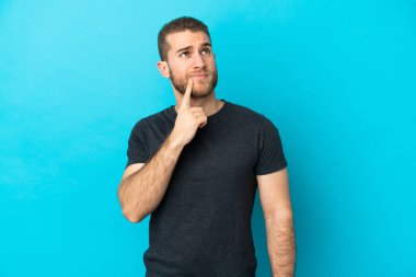 Genç, yakışıklı, beyaz bir adam mavi arka planda izole edilmiş.