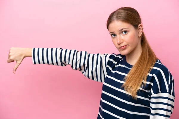 若い白人女性はピンクの背景に孤立し 否定的な表現で親指を下に示します — ストック写真
