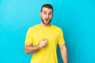 Mavi arka planda izole edilmiş yakışıklı beyaz adam kendini işaret ediyor.