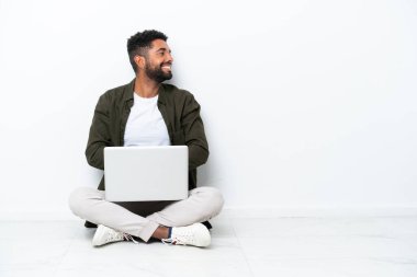 Yerde dizüstü bilgisayarı olan genç Brezilyalı bir adam.