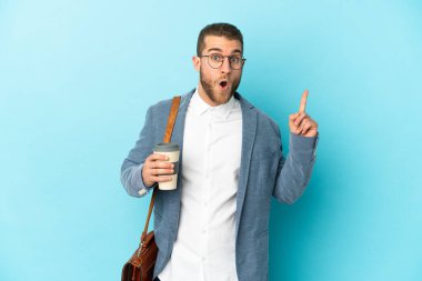 Kafkasyalı genç işadamı, mavi arka planda izole edilmiş bir şekilde bir fikri işaret ederek...