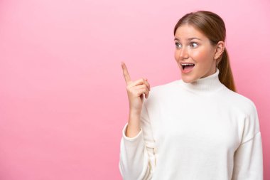 Pembe arka planda izole edilmiş genç beyaz kadın çözümü bulmak için parmağını kaldırıyor.