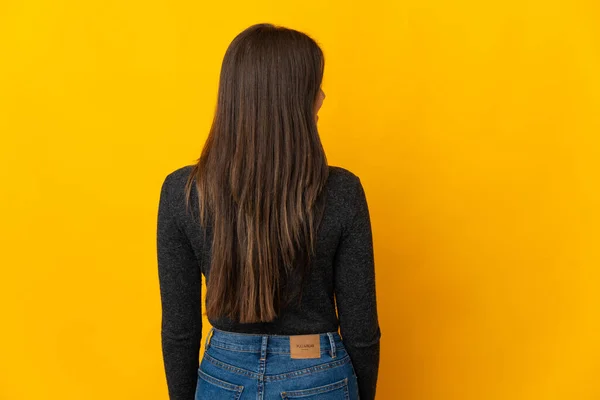 ティーンブラジル人の女の子孤立しました上の黄色の背景でバックポジションと見る側 — ストック写真