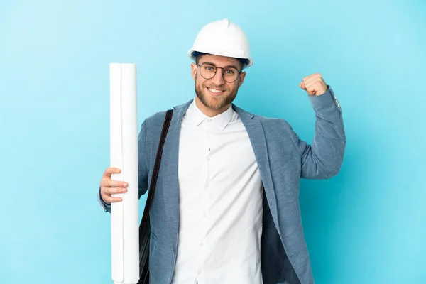 Young Architect Man Helmet Holding Blueprints Isolated Background Doing Strong — Fotografia de Stock