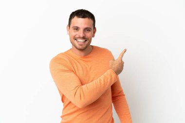 İzole edilmiş beyaz arka planı olan Brezilyalı adam şaşırmış ve işaret ediyor.