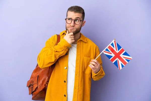 拿着英国国旗的年轻的高加索人 背景为紫色 有怀疑和思考 — 图库照片
