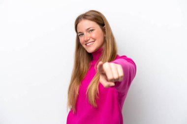 Beyaz arka planda izole genç beyaz kadın mutlu bir ifadeyle ön tarafı işaret ediyor.
