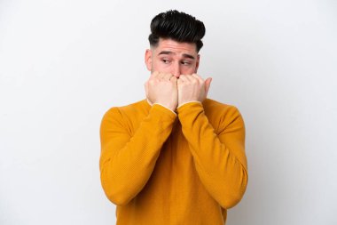 Beyaz arka planda izole edilmiş genç beyaz bir adam gergin ve korkmuş bir şekilde elleriyle suni teneffüs yapıyor.