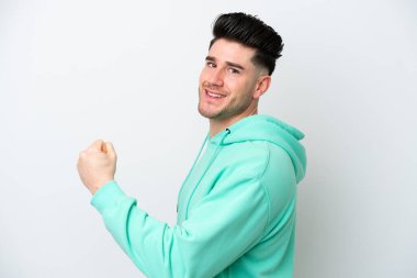 Beyaz arka planda izole edilmiş genç beyaz adam zaferi kutluyor.