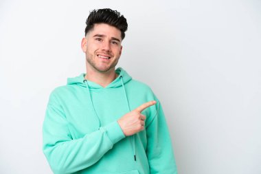 Beyaz arka planda izole edilmiş genç beyaz bir adam bir ürün sunmak için kenarı işaret ediyor.