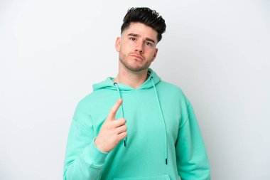 Beyaz arka planda izole edilmiş genç beyaz adam hayal kırıklığına uğramış ve ön tarafı işaret ediyor.