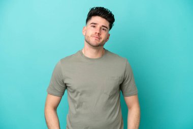 Kafkasyalı genç adam mavi arka planda tek başına gülüyor.