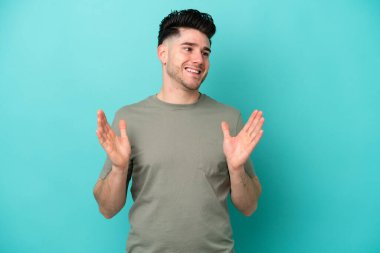 Mavi arka planda yalıtılmış beyaz bir adam. Şaşırtıcı bir yüz ifadesi var.