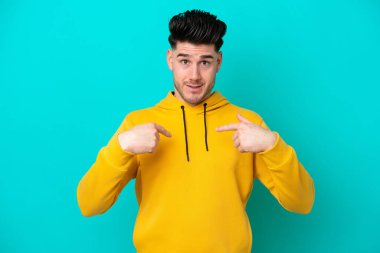 Mavi arka planda yalıtılmış beyaz bir adam. Şaşırtıcı bir yüz ifadesi var.