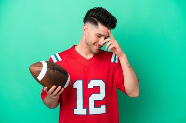 Rugby oynayan beyaz bir adam yeşil arka planda izole edilmiş gülüyor.