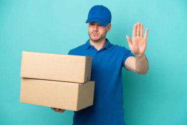 Teslimat yapan beyaz adam mavi arka planda izole edilmiş. Durma hareketi yapıyor ve hayal kırıklığına uğruyor.