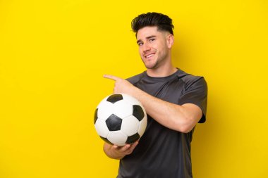 Sarı arka planda izole edilmiş yakışıklı genç futbolcu.