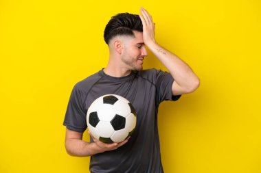 Sarı arka planda izole edilmiş yakışıklı genç futbolcu bir şey fark etti ve çözüme niyetlendi.